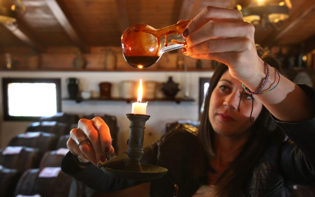 A member of the Leonardi family checks the colors of aging balsamic vinegar in the village of Magreta di Formigine in Modena - David Silverman /Getty Images Europe 