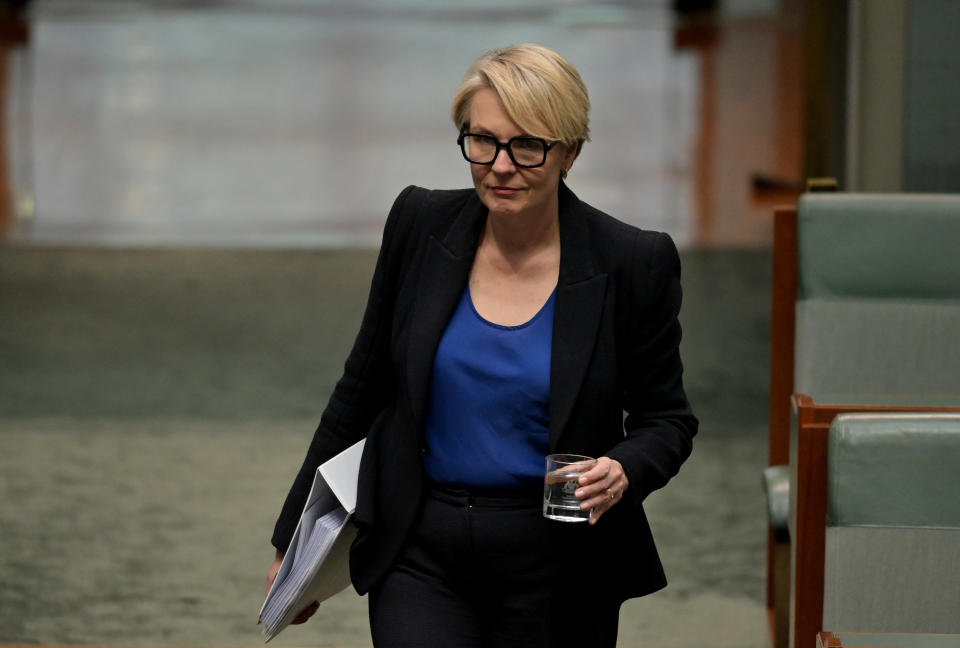 Australia’s Environment Minister Tanya Plibersek in parliament carrying a folder and glass of water.