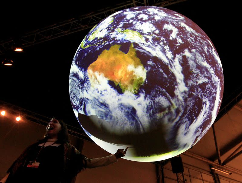 FILE PHOTO: A visitor places a finger on an illuminated globe in the hall of the conference centre in Copenhagen