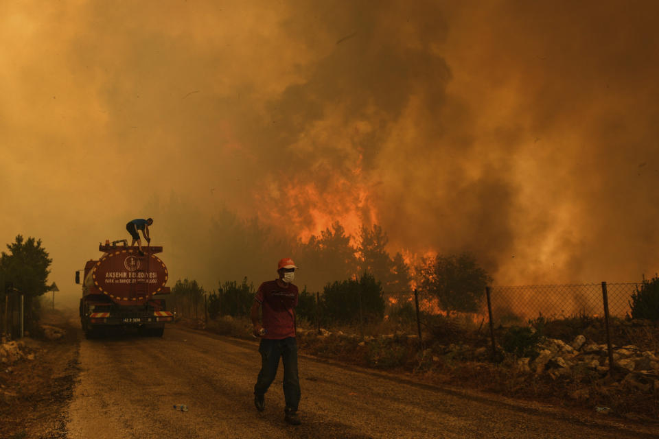 A man down a road in the fire-devastating Sirtkoy village, near Manavgat, Antalya, Turkey, Sunday, Aug. 1, 2021. More than 100 wildfires have been brought under control in Turkey, according to officials. The forestry minister tweeted that five fires are continuing in the tourist destinations of Antalya and Mugla. (AP Photo)