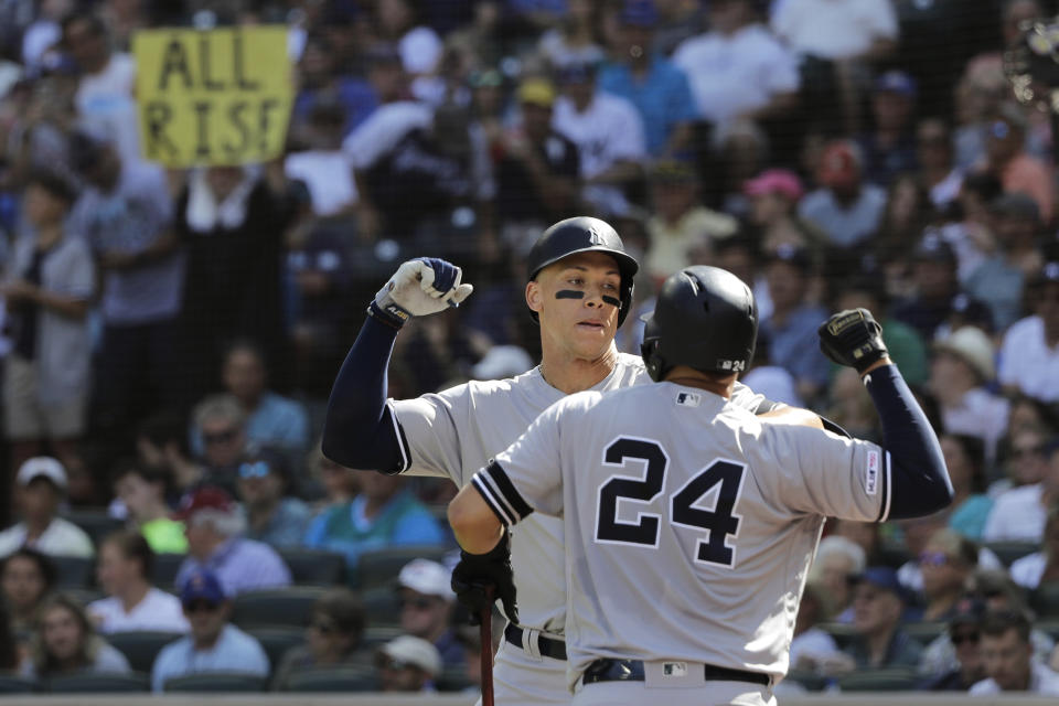 A fan holds a sign that reads "All Rise" as New York Yankees' Aaron Judge, left, greets Gary Sanchez (24) after Judge hit a two-run home run against the Seattle Mariners during the fifth inning of a baseball game, Wednesday, Aug. 28, 2019, in Seattle. (AP Photo/Ted S. Warren)
