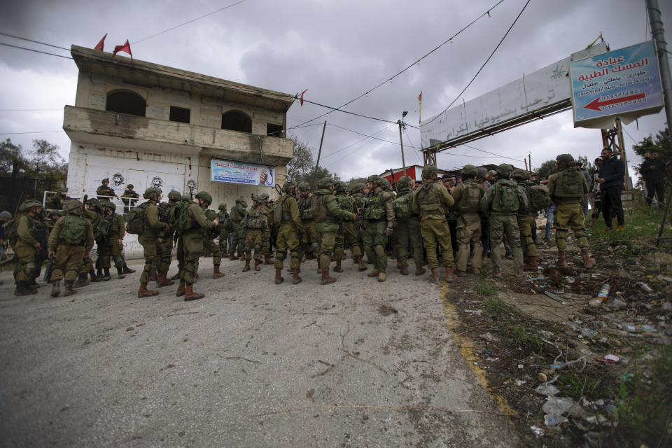 Israeli soldiers stand between Palestinians and a Jewish settlers following an attack on the West Bank village of Burqa, Friday, Dec. 17, 2021. Palestinian officials said at least two people have been injured in a string of Jewish settler attacks in northern West Bank villages, a day after an Israeli settler was shot dead by Palestinian gunmen. (AP Photo/Majdi Mohammed)