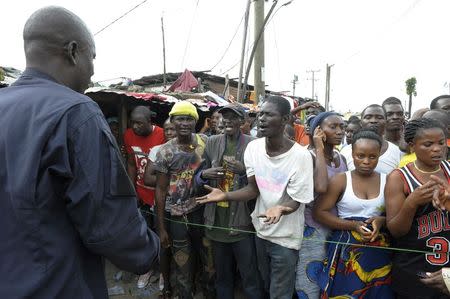 Residents, who are in an Ebola quarantine area, complain to a security officer as they wait for their relatives to bring them food and essentials, in West Point, Monrovia August 23, 2014. REUTERS/2Tango