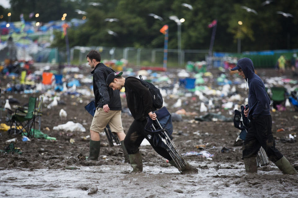 Three fans drag their belongings through the mud.