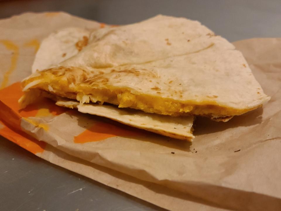 quarters of a chicken quesadilla from taco bell resting on its wrapper