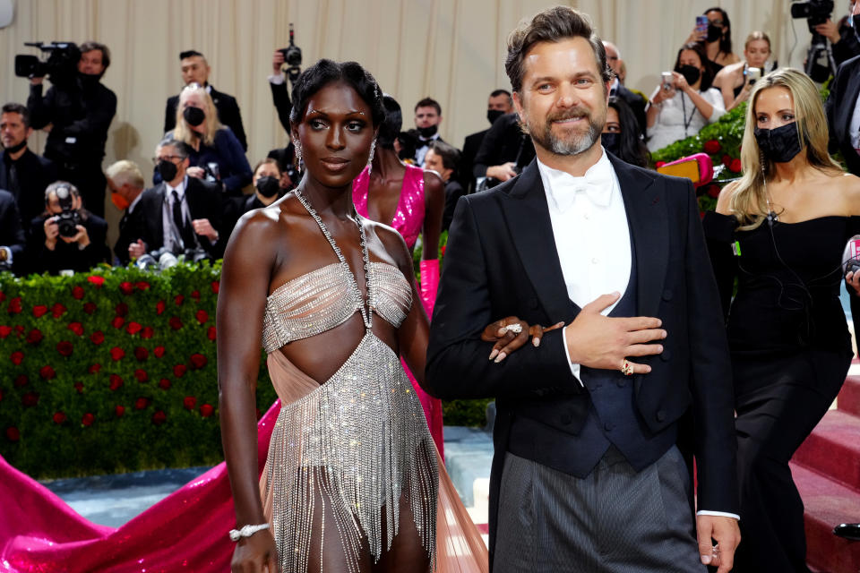 Jodie Turner-Smith in a shimmering, cut-out gown and Joshua Jackson in a classic tuxedo posing on the Met Gala red carpet