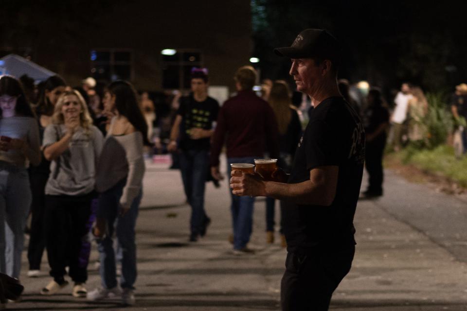 Ben Pratt, a How Bazar A La Carte night market attendee, walks down the street with beers on Oct. 14, 2023, in downtown Gainesville, Florida.