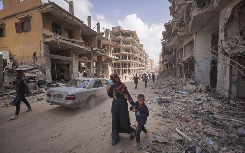 Palestinians walk past the rubble of houses destroyed by Israeli bombardment in Khan Yunis in the southern Gaza Strip