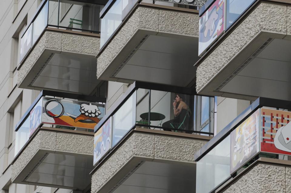 A visitor testing facilities overnight smokes a cigarette on one of the brightly decorated balconies in the Olympic Village, built for the London 2012 Olympic Games, on June 29, 2012. in Stratford, east London. The village will accomodate up to 16,000 athletes and officials from more than 200 nations. (Photo by Olivia Harris - WPA Pool/Getty Images)