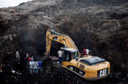 Rescue workers watch as excavators dig into a pile of garbage in search of missing people following a landslide when a mound of trash collapsed on an informal settlement at the Koshe garbage dump in Ethiopia's capital Addis Ababa, March 13, 2017. REUTERS/Tiksa Negeri