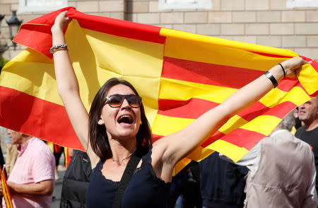 A woman holds up a joint Catalan and Spanish flag joined together during a demonstration in favor of a unified Spain a day before the banned October 1 independence referendum, in Barcelona, Spain, September 30, 2017. REUTERS/Yves Herman