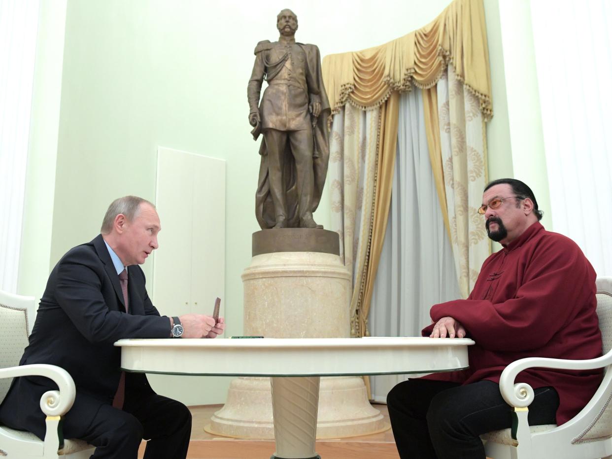 Putin holds a Russian passport before presenting it to US action hero actor Steven Seagal in Moscow in 2016.