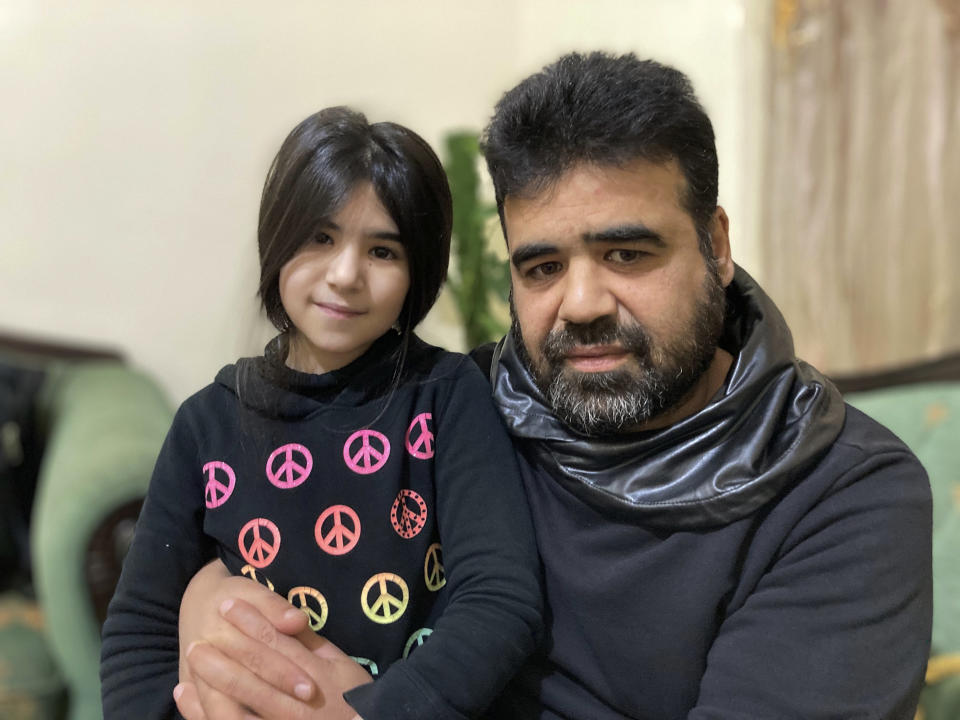 Syrian refugee Mahmoud Mansour, 47, sits with his youngest daughter Sahar, 8, at his rented apartment in Amman, Jordan, Wednesday, Jan. 20, 2021. President Joe Biden has vowed to restore America's place as a world leader in offering sanctuary to the oppressed by raising the cap on the number of refugees allowed in each year. Mansour's family had completed the work to go to the United States when the Trump administration issued its travel ban barring people from Syria indefinitely and suspending the refugee program for 120 days. (AP Photo/Omar Akour)