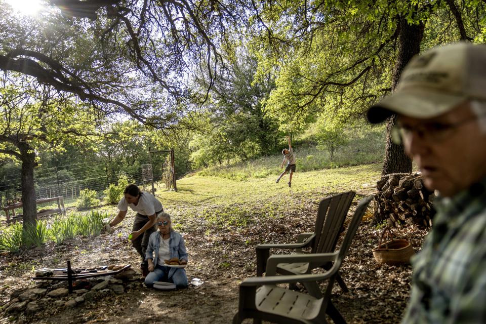 Meredith Ellis, left, prepares for a BBQ with her mother, Mary, and father, GC, right, as her son, also GC, 6, rear, plays on their ranch in Rosston, Texas, Thursday, April 20, 2023. Her parents built this ranch, and it’s where Ellis was raised, roaming with her brother through the pastures, creeks and hardwood forests as the family added land and cattle over the years. But now it’s Ellis’ turn to make the decisions. She’s implemented changes her father couldn’t dream of — because for her and other ranchers, their livelihoods and the future of the planet are on the line. (AP Photo/David Goldman)