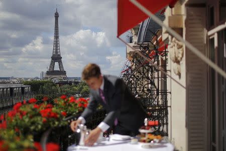 An employee prepares breakfast in front of the Eiffel tower at the Parisian luxury hotel Le Plaza Athenee, France July 30, 2015. Nowhere in the world has more accommodation available on Airbnb than Paris. Now the home-sharing website that has transformed budget travel to the French capital is giving its super-deluxe hotels a fright too. Picture taken France July 30, 2015. REUTERS/Stephane Mahe