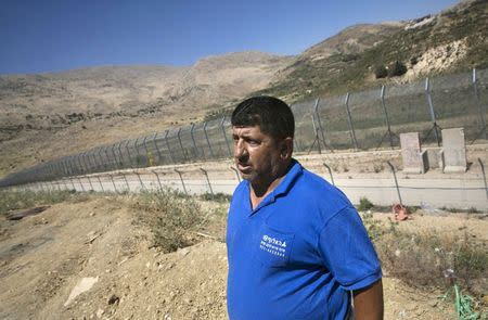 Salman, 54, a member of the Druze community, stands next to a border fence between Syria and the Israeli-occupied Golan Heights, in the Druze village of Majdal Shams, June 18, 2015. REUTERS/Baz Ratner