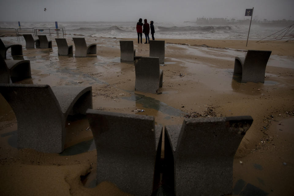 People look at the Mediterranean sea during a storm in Barcelona, Spain, Tuesday, Jan. 21, 2020. A winter storm lashed much of Spain for a third day Tuesday, leaving 200,000 people without electricity, schools closed and roads blocked by snow as it killed four people. Massive waves and gale-force winds smashed into seafront towns, damaging many shops and restaurants. (AP Photo/Emilio Morenatti)