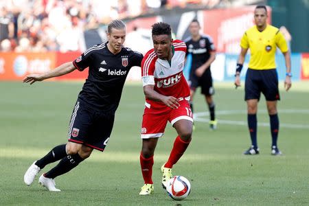 Jun 21, 2015; Washington, DC, USA; New England Revolution forward Juan Agudelo (17) dribbles the ball as D.C. United midfielder/defender Markus Halsti (4) chases in the second half at Robert F. Kennedy Memorial Stadium. D.C. United won 2-1. Geoff Burke-USA TODAY Sports