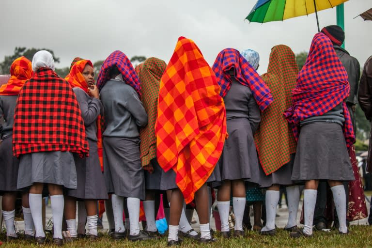 Young women gather under the rain at the University of Nairobi ahead of an open-air mass delivered by the pope on November 26, 2015