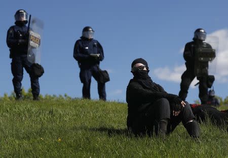 Riot police look on as a protester sits on the grass during demonstrations at the G7 Summit on the the Plains of Abraham in Quebec City, Quebec, Canada, June 8, 2018. REUTERS/Mathieu Belanger