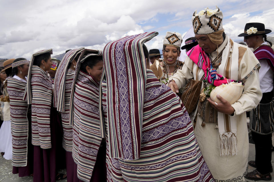 Newlyweds Carla Lozano and Wayra Larco are congratulated after performing an Aymara wedding ritual at the Killi Killli viewpoint, where they made offerings to Pachamama or Mother Earth asking for a blessed union, in La Paz, Bolivia, Saturday, March 25, 2023. According to the godmother of the wedding, Adela Callisaya, the newlyweds are reclaiming the knowledge and customs of their Aymara ancestors. (AP Photo/Juan Karita)