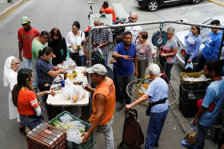 Unas personas en una fila para pagar por frutas y verduras en un mercado callejero en Caracas, nov 13, 2017. REUTERS/Marco Bello