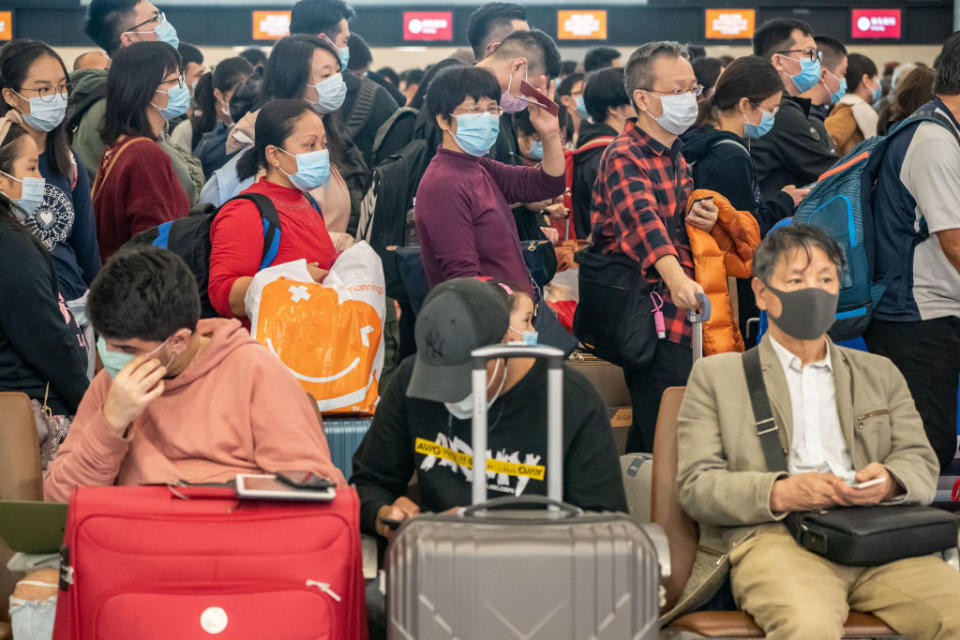 Travellers wearing face masks wait at the departure hall of West Kowloon Station in Hong Kong, China. Source: Getty