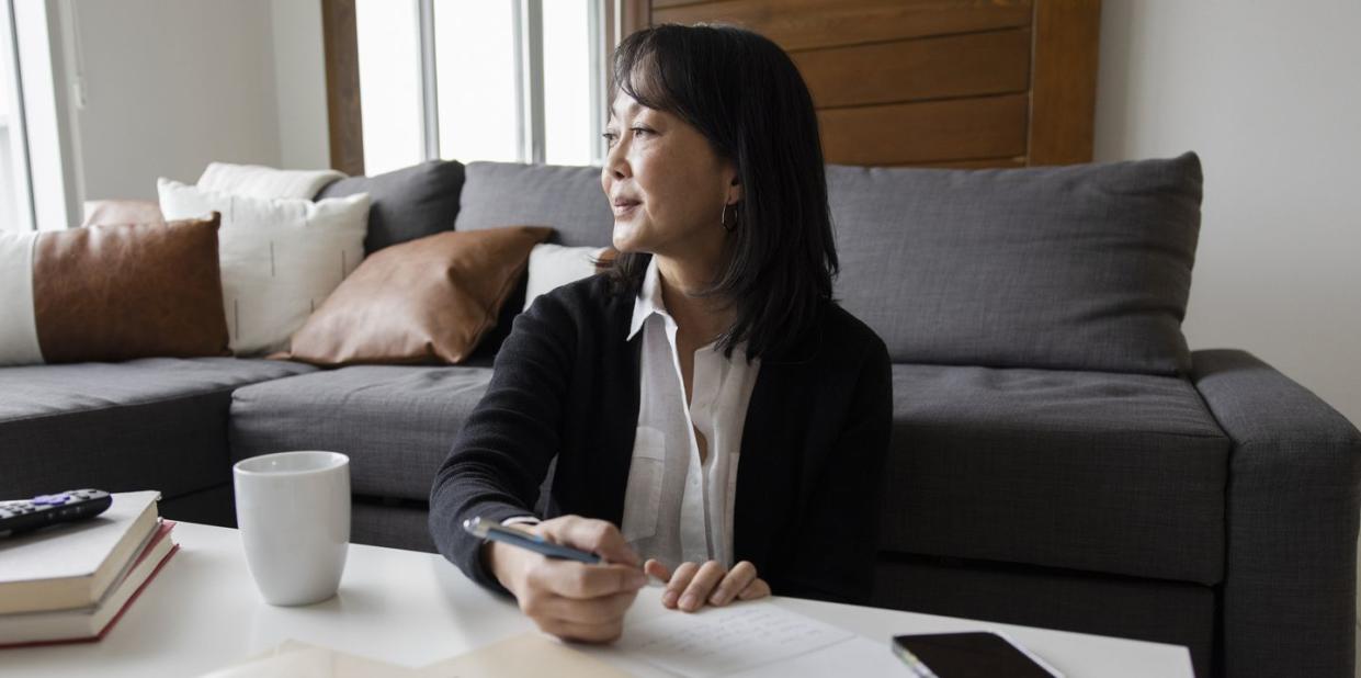 thoughtful, grateful woman writing thank you notes at home