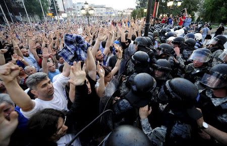 Protestors gesture to police in front of the Macedonian government building in Skopje, Macedonia May 5, 2015. Several thousand people protested in front of the building on Tuesday demanding the resignation of Prime Minister Nikola Gruevski, who was accused by the top opposition leader of trying to cover up the death of a 22-year-old who was beaten by a police member in 2011, local media reported. REUTERS/Ognen Teofilovski