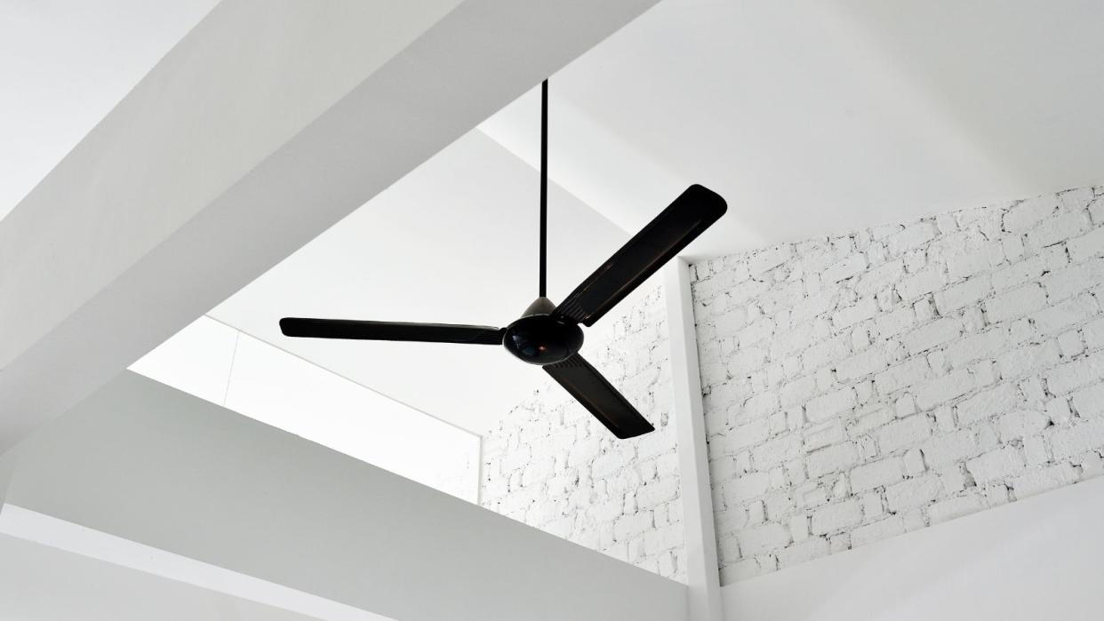  A black ceiling fan on a white brick pitched roof 