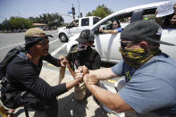 Demonstrators hold hands at an intersection Thursday June, 4, 2020 in Santa Clarita, Calif., during a protest over the death of George Floyd who died May 25 after he was restrained by Minneapolis police. (AP Photo/Marcio Jose Sanchez)