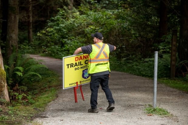 A Vancouver Parks worker removes a sign while reopening trails in Stanley Park in Vancouver on Monday. (Ben Nelms/CBC - image credit)