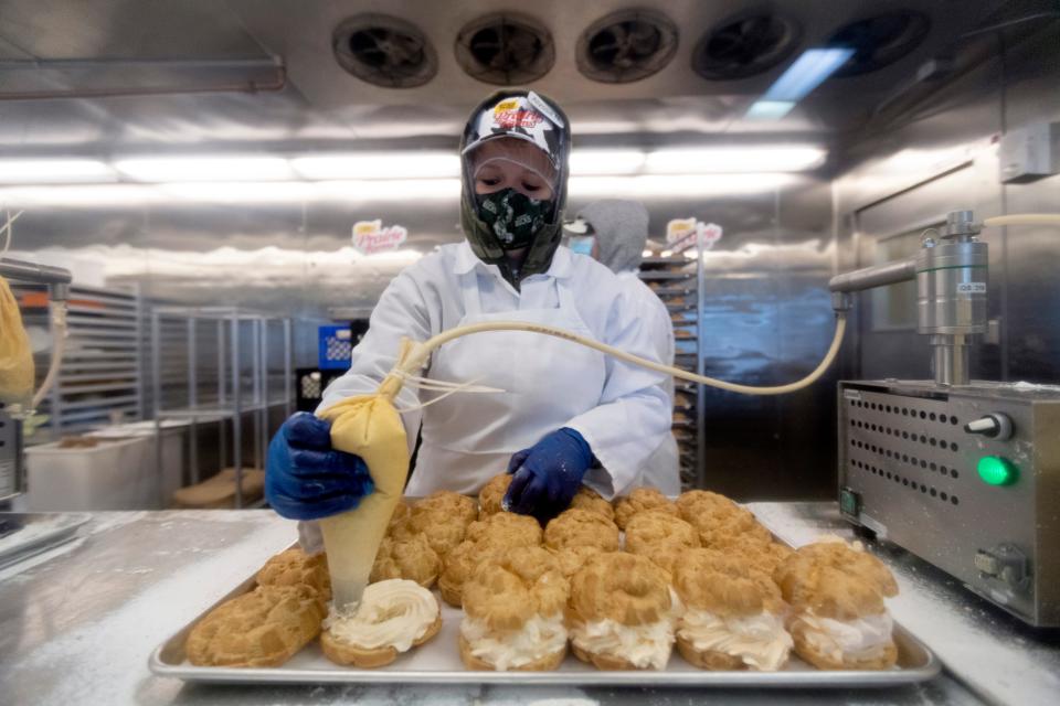 A worker fills pumpkin spice cream puffs in October 2020 at State Fair Park in West Allis. Pumpkin spice is back, along with latte cream puffs, during this year's Harvest Fair.