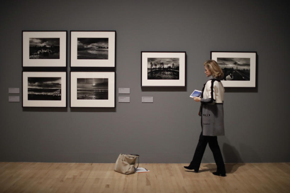 A visitor looks at landscape photographs by veteran British conflict photographer Don McCullin at the launch of his retrospective exhibition at the Tate Britain gallery in London, Monday, Feb. 4, 2019. The exhibition includes over 250 of his black and white photographs, including conflict images from the Vietnam war, Northern Ireland, Cyprus, Lebanon and Biafra, alongside landscape and still life images. (AP Photo/Matt Dunham)