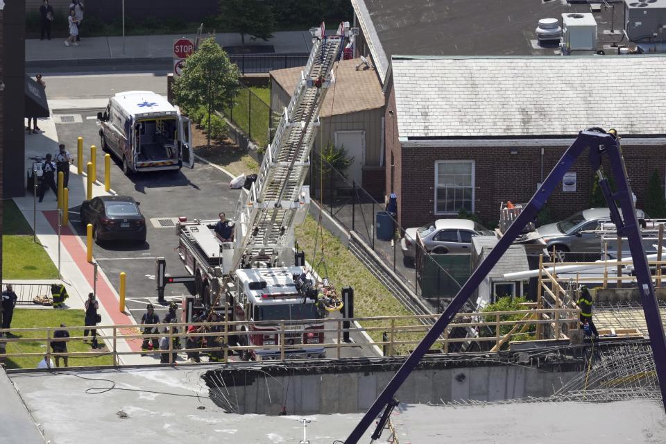 Firefighters rescue a worker after the partial collapse of a building under construction, Friday, June 2, 2023, in New Haven, Conn. The building, near the Yale School of Medicine, partially collapsed when a concrete pour went awry, foreground, injuring eight people including two critically, city officials said, adding there were no fatalities. (Paul Haring via AP)