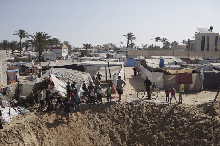 Palestinos se reúnen al borde de un cráter tras un ataque aéreo israelí en una zona donde se refugian personas desplazadas en Khan Younis, sur de la Franja de Gaza, viernes 21 de junio de 2024.