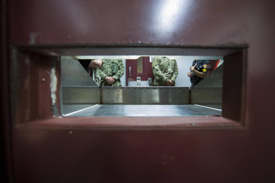 FILE - In this April 17, 2019, file photo reviewed by U.S. military officials, U.S. soldiers stand as seen through the splash guard opening in a cell door, inside the Camp V detention facility in Guantanamo Bay Naval Base, Cuba. The White House says it intends to shutter the prison on the U.S. base in Cuba, which opened in January 2002 and where most of the 39 men still held have never been charged with a crime. (AP Photo/Alex Brandon, File)