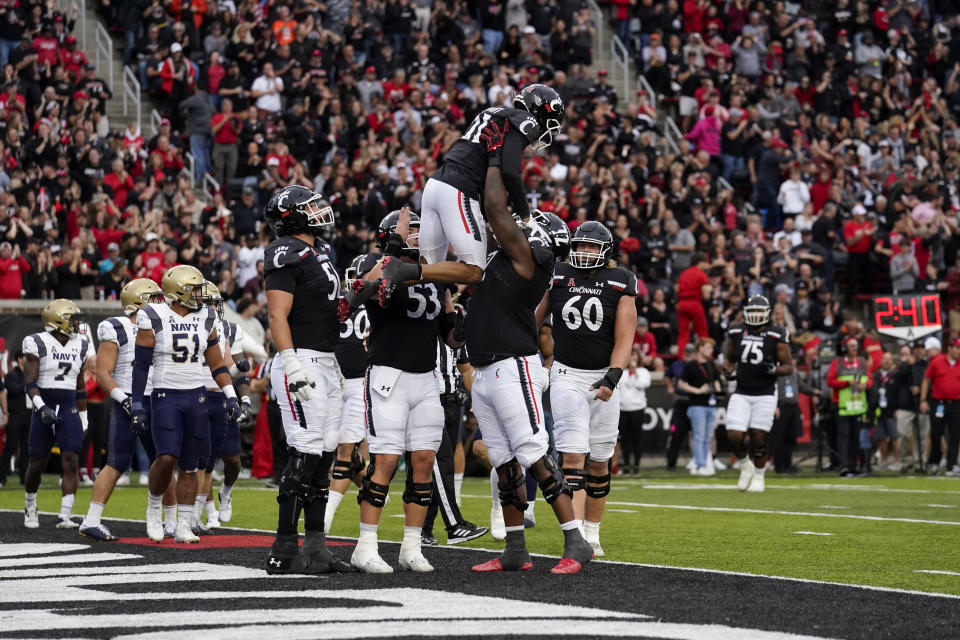 Cincinnati wide receiver Tyler Scott, top, celebrates with teammates after scoring a touchdown during the first half of an NCAA college football game against Navy, Saturday, Nov. 5, 2022, in Cincinnati. (AP Photo/Jeff Dean)