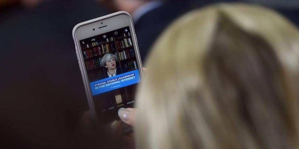 A member of the audience watches on her smart phone as Britain's Prime Minister Theresa May delivers a campaign speech at the Royal United Services Institute (RUSI) in central London, Britain, June 5, 2017. REUTERS/Hannah McKay