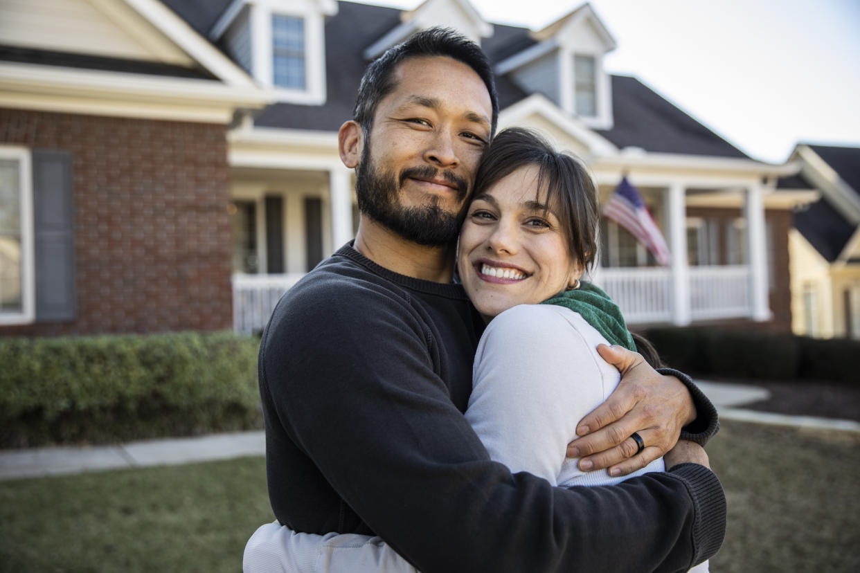 Husband and wife embracing in front of home