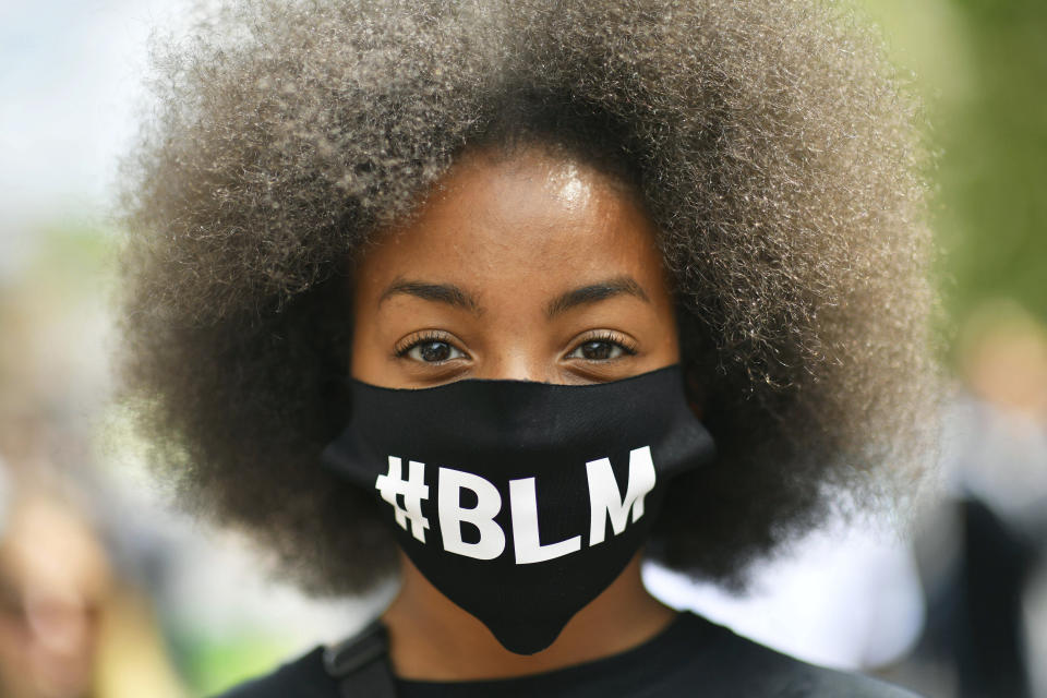 A protestor wearing a face mask to protect against coronavirus, takes part in a Black Lives Matter protest rally on College Green, Bristol, England, Sunday June 7, 2020, in response to the recent killing of George Floyd by police officers in Minneapolis, USA, that has led to protests in many countries and across the US. (Ben Birchall/PA via AP)