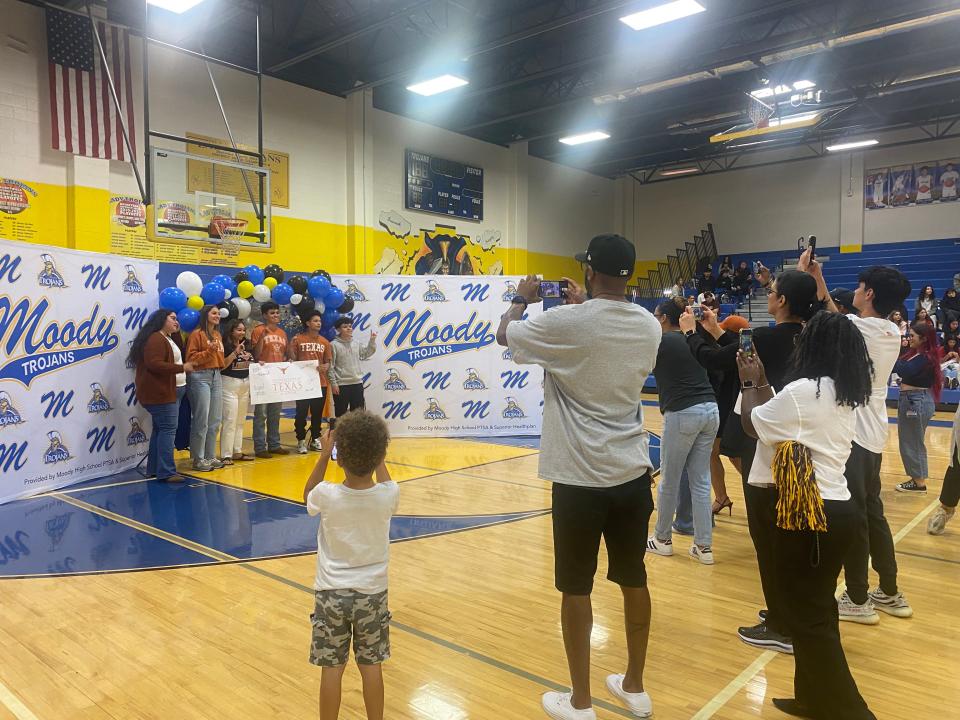 Parents and friends hurry to snap a photo of Moody High School seniors who plan to attend the University of Texas after graduation at Moody High School's senior signing celebration Friday.