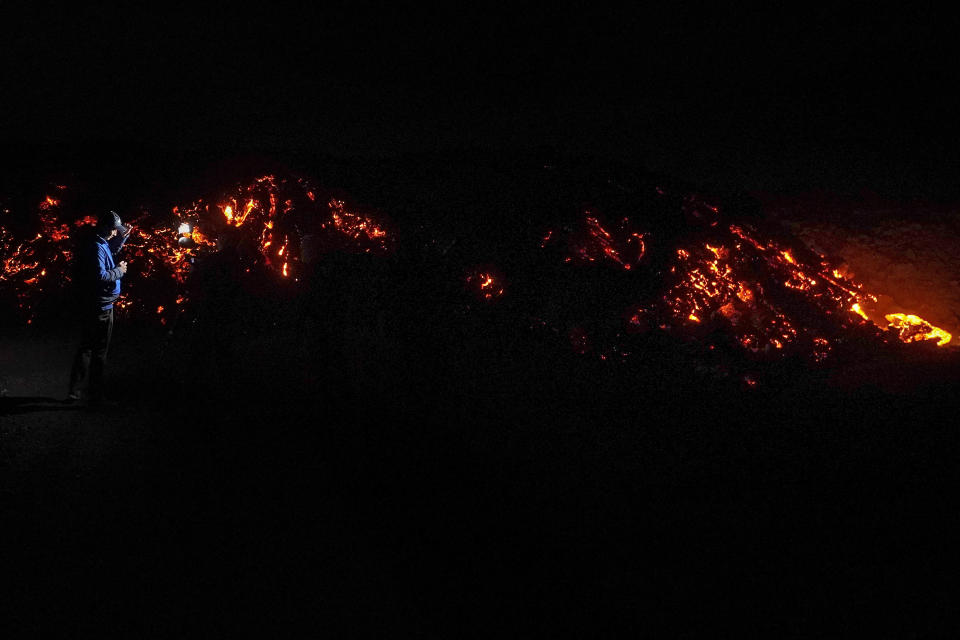 A journalist, left, records lava from the Mauna Loa volcano as it erupts Wednesday, Nov. 30, 2022, near Hilo, Hawaii. (AP Photo/Gregory Bull)