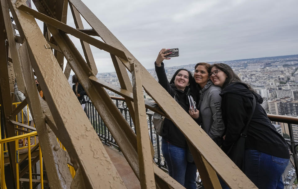 Visitors take a selfie with a phone from the Eiffel Tower in Paris, Friday, July 16, 2021. The Eiffel Tower is reopening Friday for the first time in nine months, just as France faces new virus rules aimed at taming the fast-spreading delta variant. The "Iron Lady" was ordered shut in October as France battled its second surge of the virus. (AP Photo/Michel Euler)