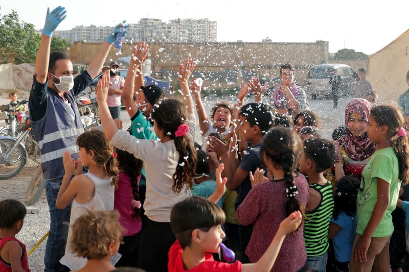 A volunteer entertains internally displaced children, amid concerns over the spread of the coronavirus disease (COVID-19), at an IDP camp in Idlib