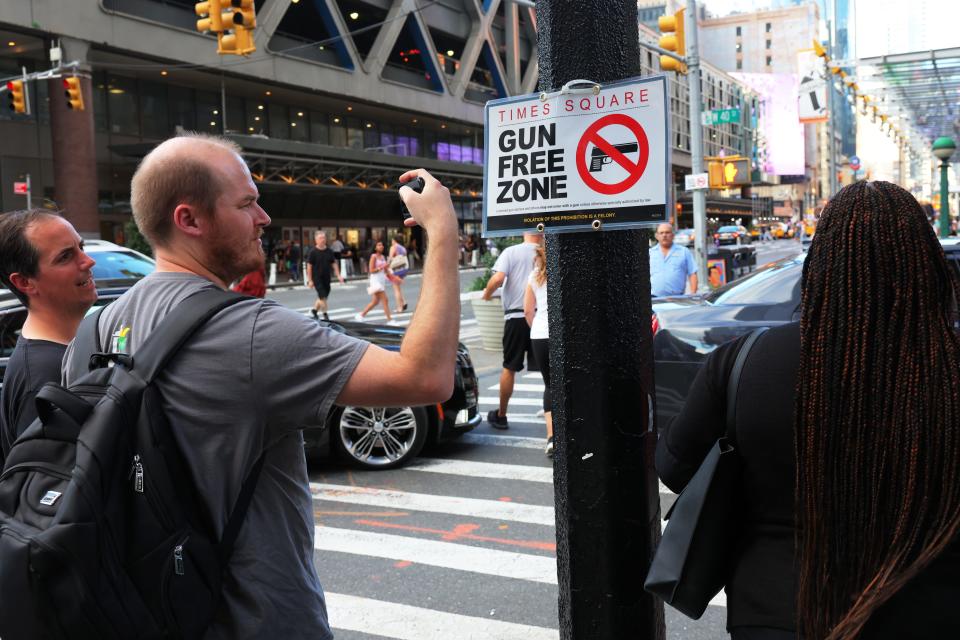 A person takes a photo of a "Gun Free Zone" sign posted on 40th Street and 8th Avenue in New York City. The signs were posted at every entry and exit point in Times Square as a New York law limiting where firearms can be legally carried in public is set to go into effect on Thursday.