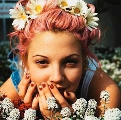 <p>Une jeune Drew Barrymore innove avec des cheveux pastel et une couronne de fleurs à Coachella.<i> (Photo : Pinterest)</i></p>