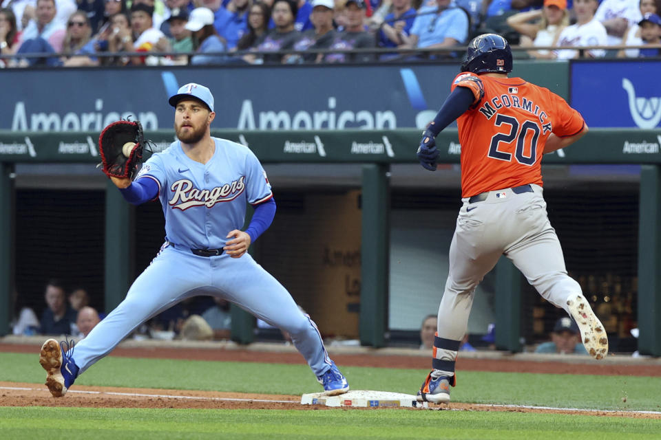 Texas Rangers first baseman Jared Walsh, left, gets the throw from third for an out against Houston Astros' Chas McCormick (20) in the second inning of a baseball game Sunday, April 7, 2024 in Arlington, Texas. (AP Photo/ Richard W. Rodriguez)