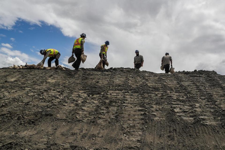 Crews place sandbags atop a newly built levee.