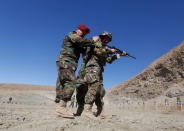 A member of Afghan army Special Forces helps the new recruits to the Afghan army Special Forces take part in a military exercise in Rishkhur district outside Kabul, Afghanistan February 25, 2017. Picture taken on February 25, 2017. REUTERS/Omar Sobhani